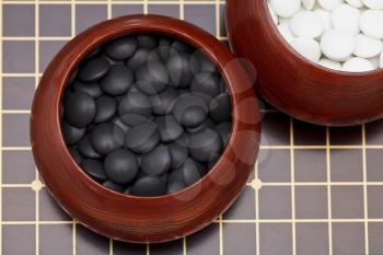 black double convex yunzi stones in wooden bowl on go board