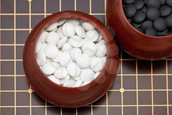 white double convex yunzi stones in wooden bowl on go board