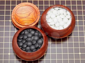 top view of black and white go game stones in wooden bowls