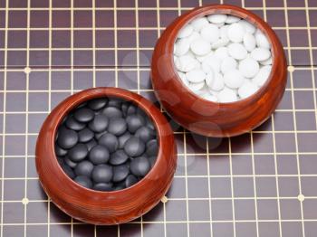 set of black and white go game stones in wooden bowls