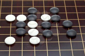 position of stones during go game playing on wooden goban