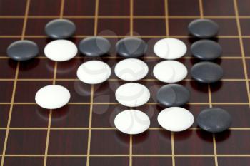 many black and white stones during go game playing on goban close up