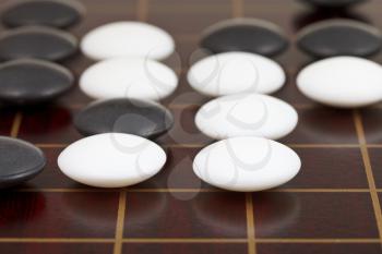 position of stones during go game playing on wooden desk close up