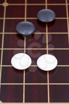 four stones during go game playing on dark wooden board
