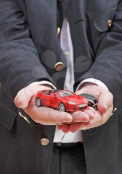 red car and key in seller's hand close up