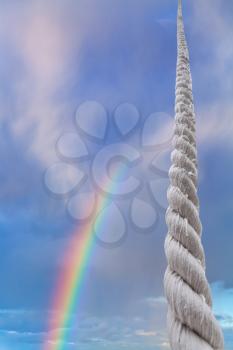 thick cord rises in blue sky with rainbow