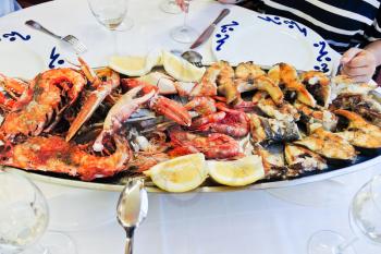 plate with cooked seafood - grilled fish, prawns, lobster, langoustine