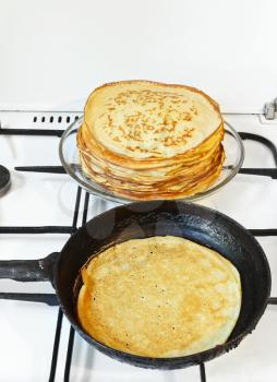 pancake in pan and stack of prepared pancakes close up