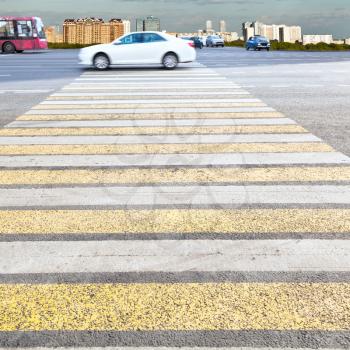 yellow and white crossing zebra of pedestrian crosswalk on urban street