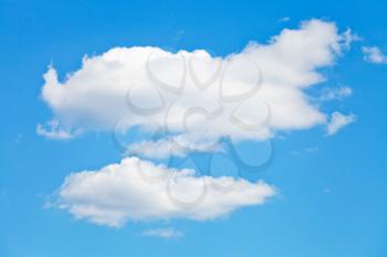 two puffy white clouds in blue summer sky