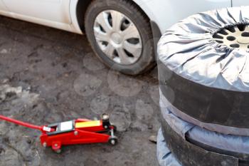 seasonal replacement of car tires with jack outdoors - preparation for repair