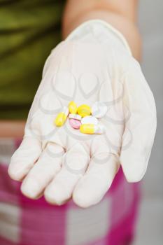 several pills in gloved hand close up