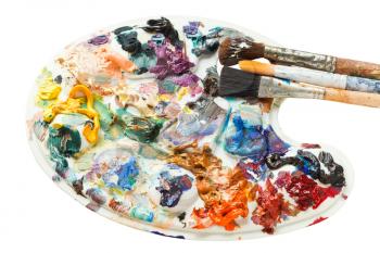used artistic pallette with oil paints and paintbrushes isolated on white background