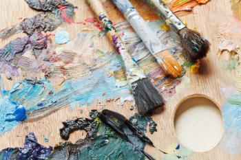 three old paintbrushes on used oils artistic palette