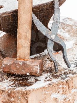 blacksmith anvil, tongs and hammer in old country smithy in winter