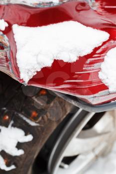 crumpled fender of red car after winter traffic accident