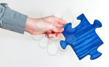 blue painted puzzle piece in female hand on grey background