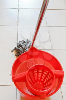 red bucket with washing water and mopping the tile floors