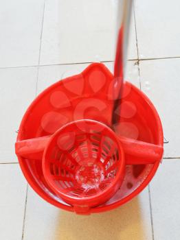 mop in red bucket with washing water on tile floor