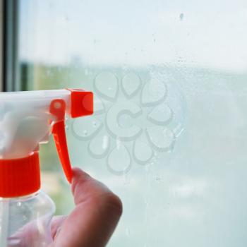 washing home window - liquid jet from spray bottle on glass
