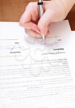 buyer signs an agreement by silver pen on table