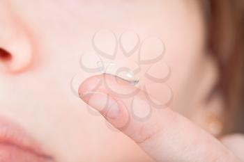 contact lens on finger near female face close up