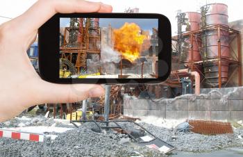 travel concept - tourist taking photo of explosion at factory on mobile gadget