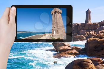 travel concept - tourist taking photo of Lighthouse on Pink Granite Coast in Brittany on mobile gadget, France