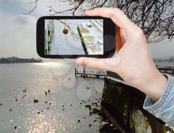 travel concept - tourist taking photo of Lake Geneva in winter on mobile gadget, Switzerland