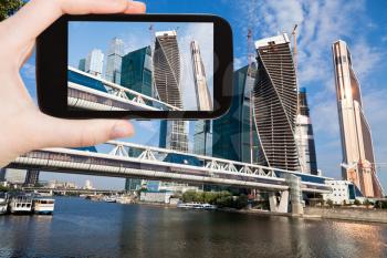 travel concept - tourist taking photo of new Moscow City district and bagration bridge on mobile gadget, Russia