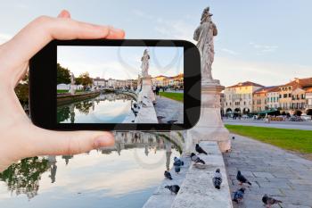travel concept - tourist taking photo of Prato della Valle in Padua, Italy on mobile gadget