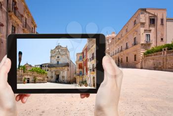 travel concept - tourist taking photo of medieval Episcopal Palace in Syracuse on mobile gadget