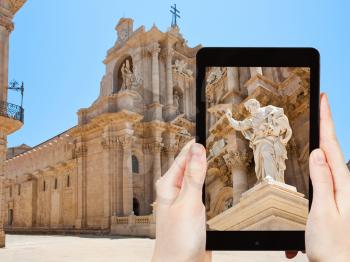 travel concept - tourist taking photo of Apostle statue in Cathedral in Syracuse, Sicily on mobile gadget