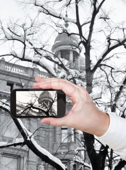 travel concept - tourist taking photo of snow on bare tree in Zurich city on mobile gadget Switzerland