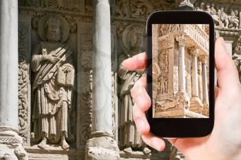 travel concept - tourist takes picture of Romanesque column in Church of Saint Trophime, Arles, France on smartphone,