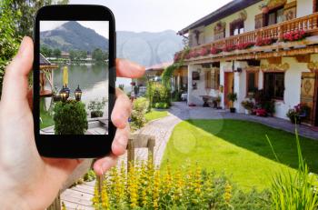 travel concept - tourist takes picture of Schliersee lake in Bavaria on smartphone, Germany
