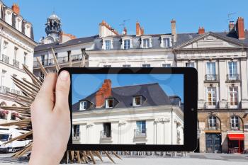 travel concept - tourist takes picture of facade of old urban house in Nantes city, France on smartphone,