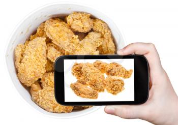 photographing food concept - tourist takes picture of hot fried chicken wings in basket on smartphone, USA