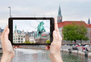 travel concept - tourist takes picture of Statue of Absalon on Hojbro square and Frederiksholms Kanal in Copenhagen, Denmark on tablet pc