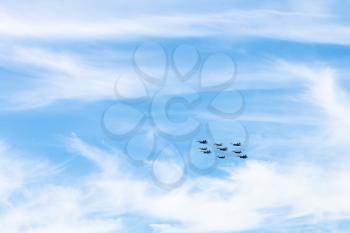 flight of military low-flying aircrafts in white clouds in blue sky