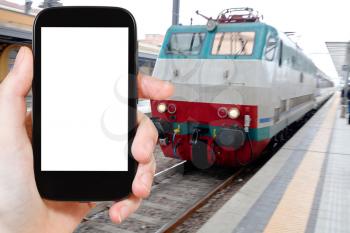 travel concept - tourist photograph suburban electric train on railway station in Parma, Italy on smartphone with cut out screen with blank place for advertising logo