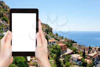 travel concept - tourist photograph Taormina city from Castelmola villige, Sicily, Italy on tablet pc with cut out screen with blank place for advertising logo