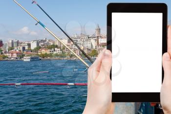 travel concept - tourist photograph fishermen on Galata bridge in Istanbul, Turkey on tablet pc with cut out screen with blank place for advertising logo