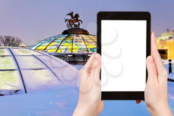 travel concept - tourist photograph cupola with Saint George and the Dragon on Manege square in Moscow, Russia in winter evening on tablet pc with cut out screen with blank place for advertising logo