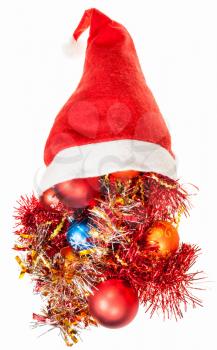 christmas gifts - xmas balls and decorations spill over red santa hat on white background