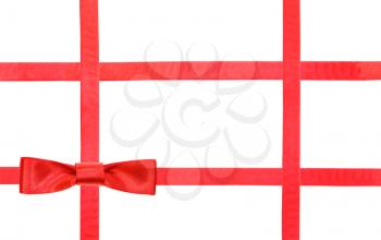 one red satin bow knot in lower left corner and four intersecting ribbons isolated on horizontal white background