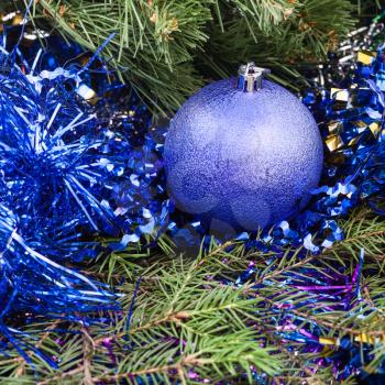 Christmas still life - one violet Christmas bauble, tinsel on Xmas tree background