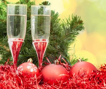 Christmas still life - Two glasses of champagne with red Xmas decorations on Christmas tree and blurred yellow background
