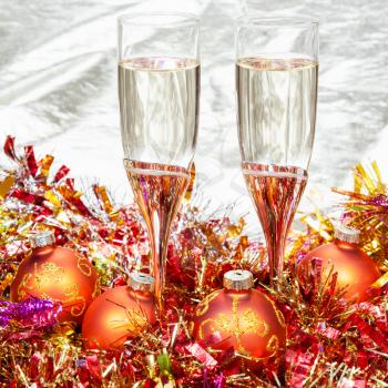 Christmas still life - Two glasses of sparkling wine with orange Xmas decorations on gold background