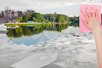 season concept - hand deletes ice floe in winter river by pink cloth from image and summer river is appearing